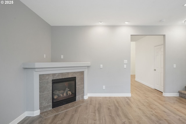 unfurnished living room featuring a tiled fireplace and light hardwood / wood-style floors