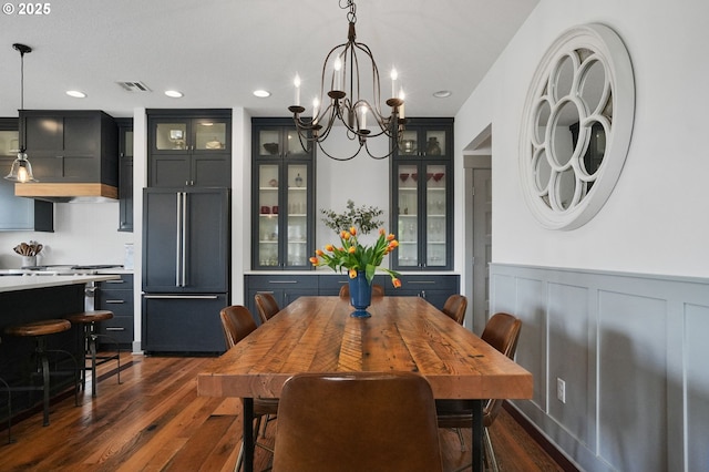 dining space with dark wood-type flooring, wainscoting, a chandelier, recessed lighting, and a decorative wall