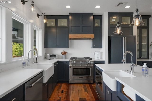 kitchen with premium appliances, a sink, dark wood-type flooring, decorative light fixtures, and recessed lighting