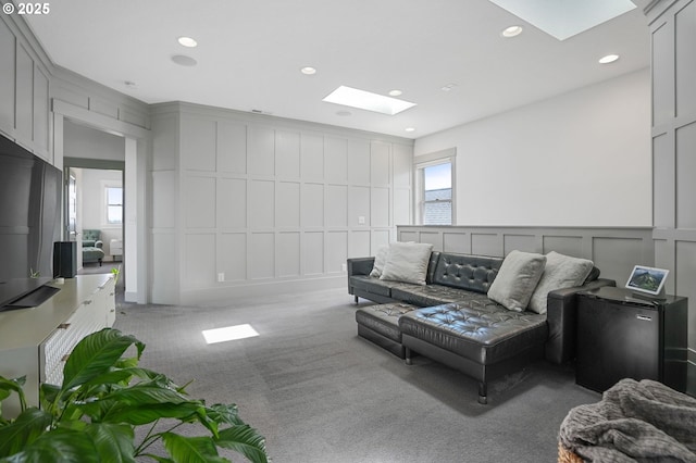 carpeted living room featuring a decorative wall, a skylight, and recessed lighting