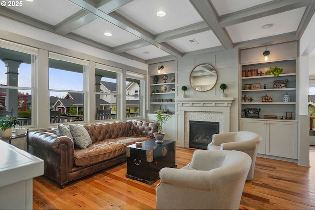 living area featuring light wood-style flooring, a tile fireplace, beam ceiling, coffered ceiling, and recessed lighting