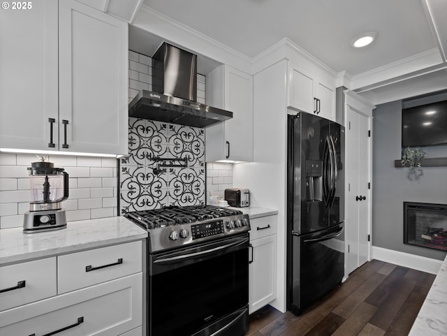 kitchen featuring wall chimney range hood, black appliances, light stone countertops, ornamental molding, and white cabinets