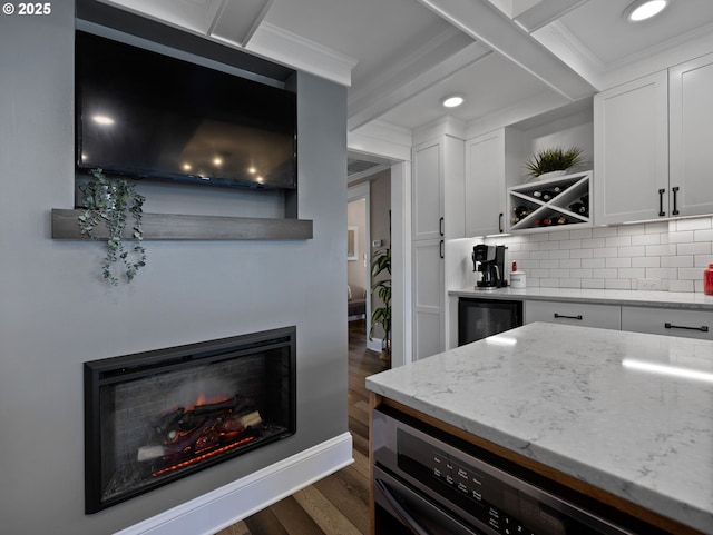 kitchen with beam ceiling, white cabinets, backsplash, and light stone countertops