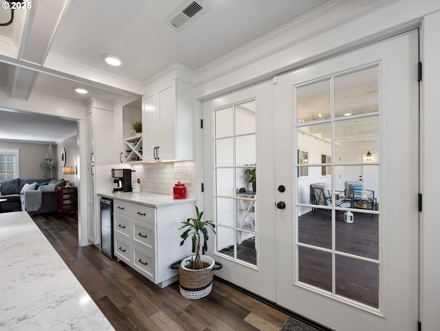 doorway with beverage cooler, dark hardwood / wood-style flooring, beamed ceiling, french doors, and ornamental molding