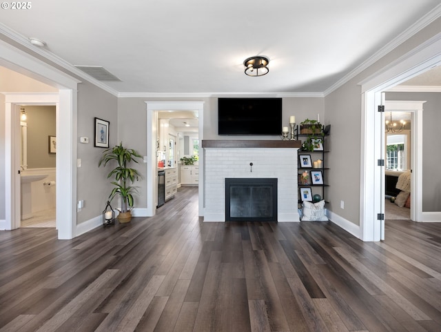 unfurnished living room with beverage cooler, an inviting chandelier, a fireplace, dark hardwood / wood-style floors, and ornamental molding