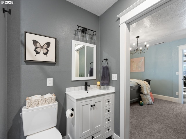 bathroom with a textured ceiling, toilet, vanity, and an inviting chandelier