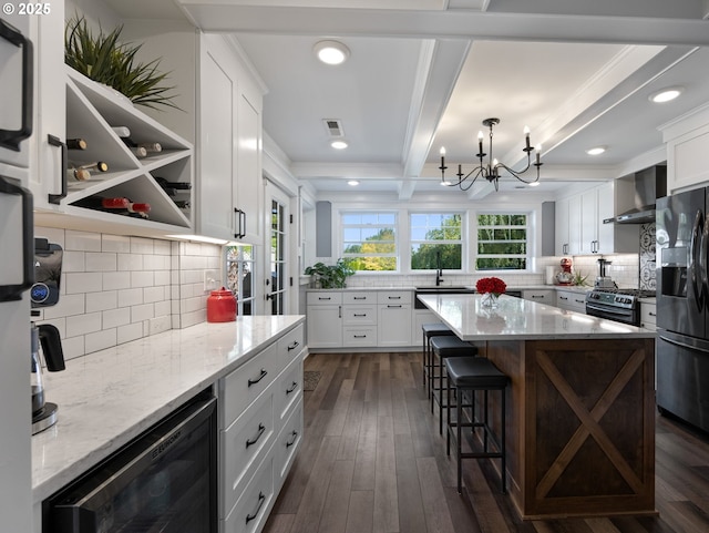 kitchen with wall chimney range hood, appliances with stainless steel finishes, a kitchen island, white cabinetry, and beverage cooler