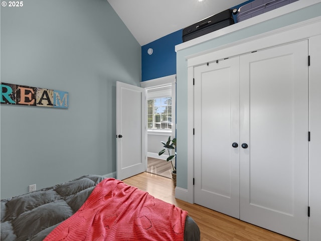 bedroom with wood-type flooring, a closet, and vaulted ceiling