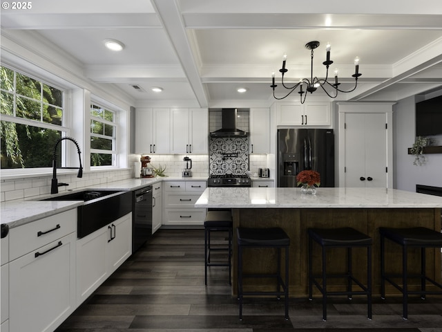 kitchen with black dishwasher, fridge with ice dispenser, a kitchen island, wall chimney exhaust hood, and light stone counters