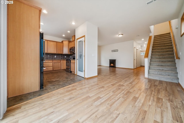 kitchen with visible vents, wood finished floors, stainless steel appliances, open floor plan, and backsplash