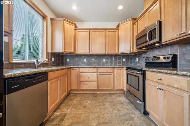 kitchen featuring tasteful backsplash, light brown cabinets, a sink, stainless steel appliances, and stone counters