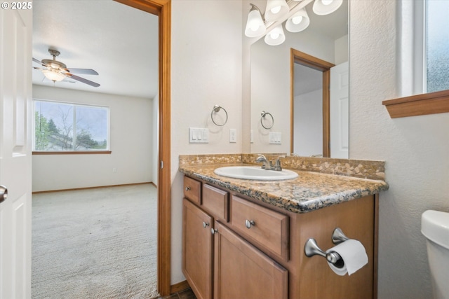 bathroom with toilet, ceiling fan, vanity, and baseboards