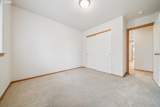 unfurnished bedroom with a closet, carpet flooring, and baseboards