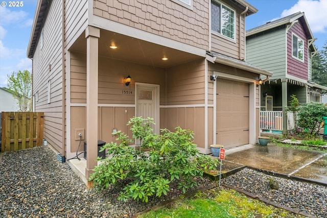 doorway to property featuring an attached garage and fence