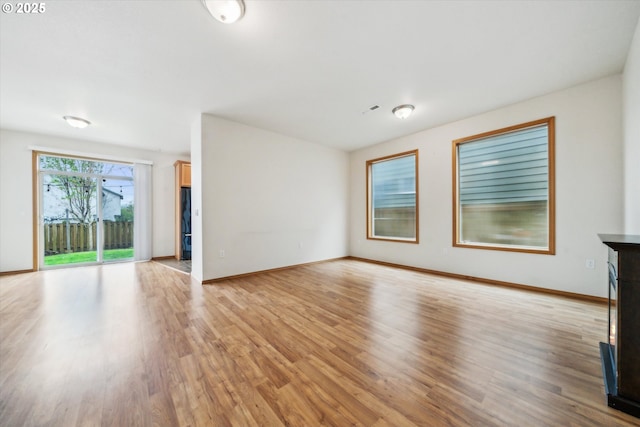 unfurnished living room with light wood-style flooring and baseboards