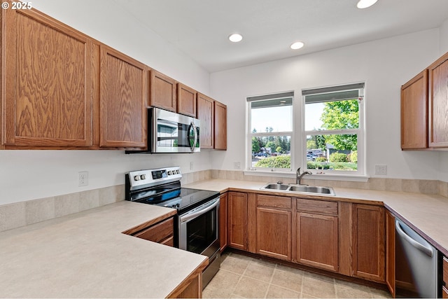 kitchen featuring stainless steel appliances, a sink, brown cabinets, light countertops, and recessed lighting