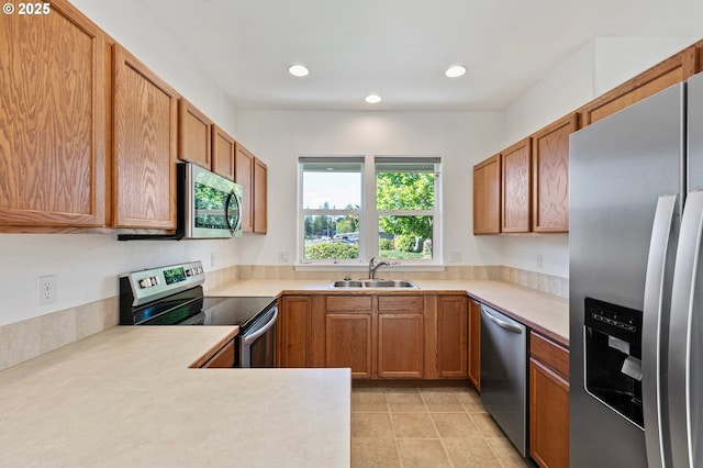 kitchen with appliances with stainless steel finishes, a sink, light countertops, brown cabinets, and recessed lighting