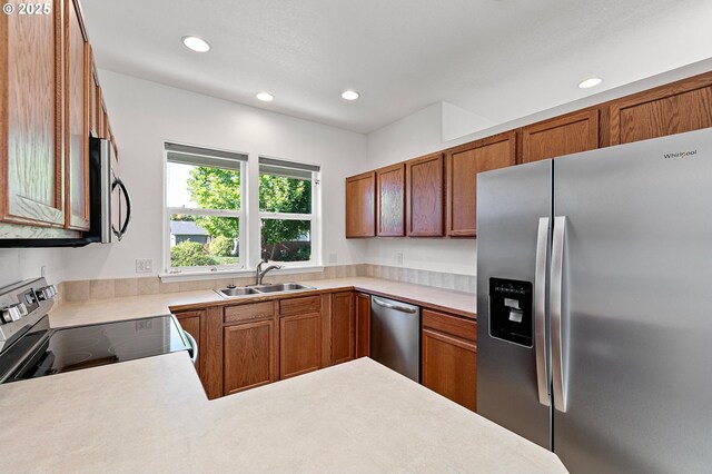 kitchen with appliances with stainless steel finishes, a sink, recessed lighting, light countertops, and brown cabinets
