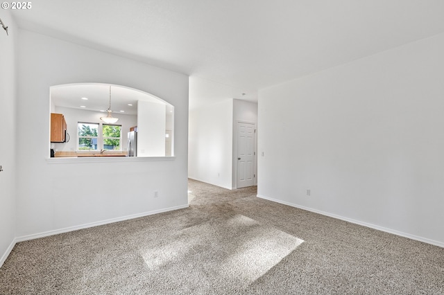 carpeted spare room featuring baseboards, recessed lighting, and arched walkways