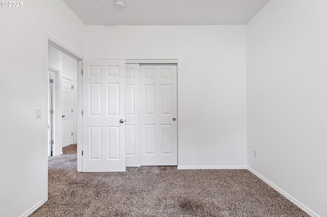 unfurnished bedroom with carpet flooring, a closet, and baseboards