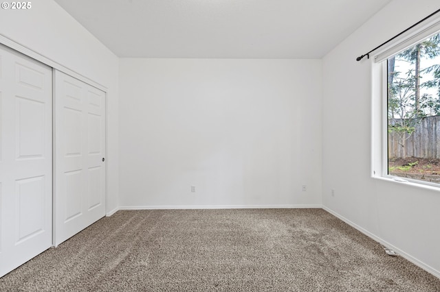 unfurnished bedroom featuring carpet, baseboards, and a closet