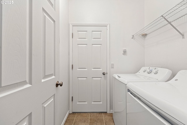 clothes washing area with separate washer and dryer, light tile patterned flooring, and baseboards