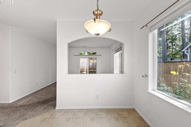 carpeted spare room with baseboards and arched walkways