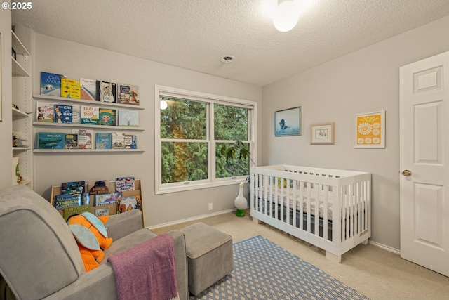 bedroom with a nursery area, a textured ceiling, and carpet