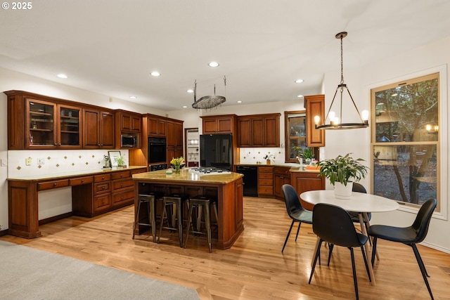 kitchen with a kitchen island, tasteful backsplash, black appliances, and pendant lighting