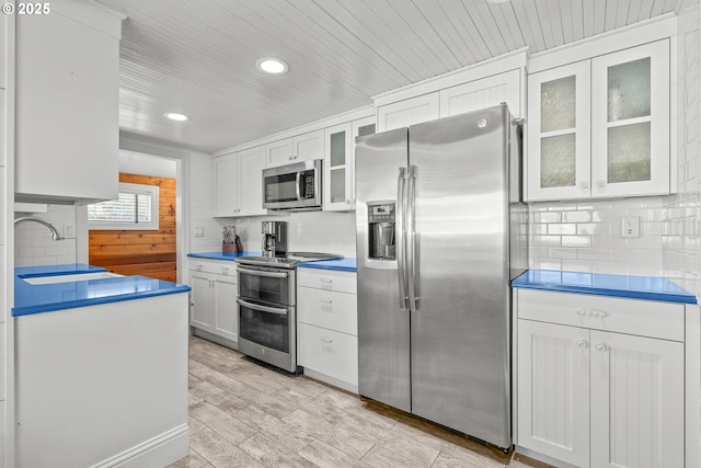 kitchen with tasteful backsplash, a sink, white cabinetry, and stainless steel appliances