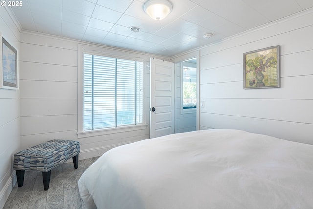 bedroom with wood finished floors, baseboards, and ornamental molding