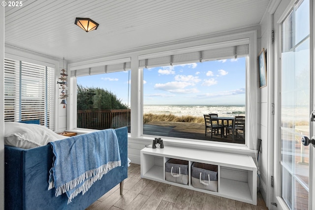 interior space with a water view, a beach view, and wood finished floors