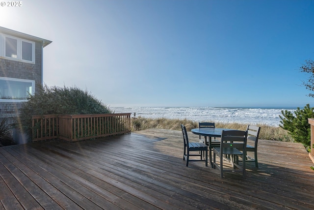 wooden terrace with a view of the beach, outdoor dining space, and a water view
