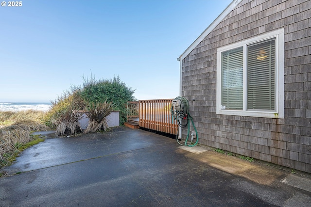 view of patio with a beach view and a deck with water view