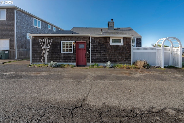 rear view of property featuring a chimney and fence