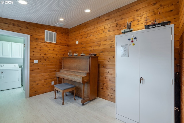 sitting room featuring light wood-style floors, visible vents, recessed lighting, washer / dryer, and wooden walls