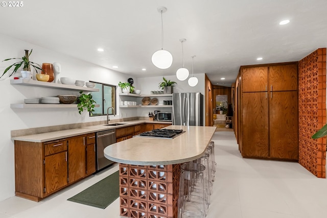 kitchen featuring open shelves, a breakfast bar area, brown cabinets, a sink, and appliances with stainless steel finishes
