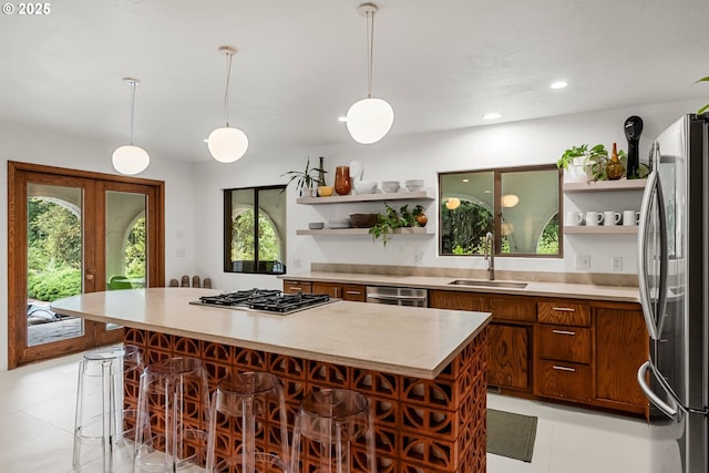 kitchen featuring open shelves, appliances with stainless steel finishes, a sink, a breakfast bar area, and light countertops