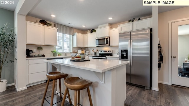 kitchen featuring dark wood-style flooring, a breakfast bar area, appliances with stainless steel finishes, white cabinetry, and a kitchen island