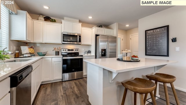 kitchen with dark wood-type flooring, appliances with stainless steel finishes, a breakfast bar, and a sink