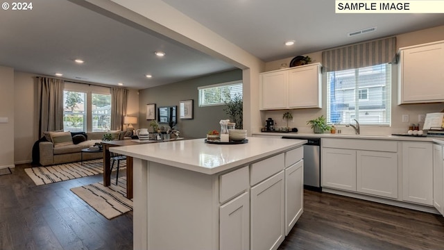 kitchen with dark wood-style floors, light countertops, stainless steel dishwasher, white cabinetry, and a sink