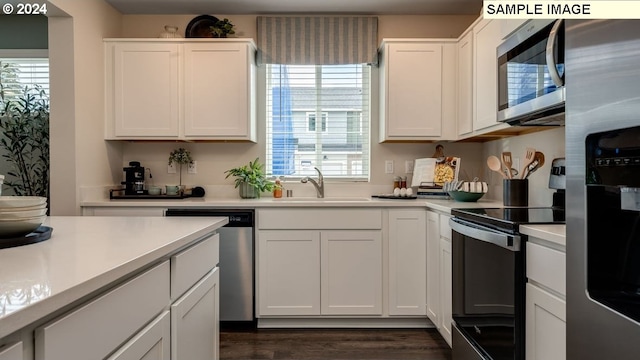 kitchen with stainless steel appliances, white cabinets, light countertops, and a sink