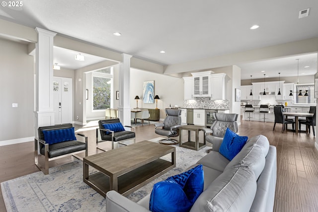 living area featuring recessed lighting, wood finished floors, and ornate columns