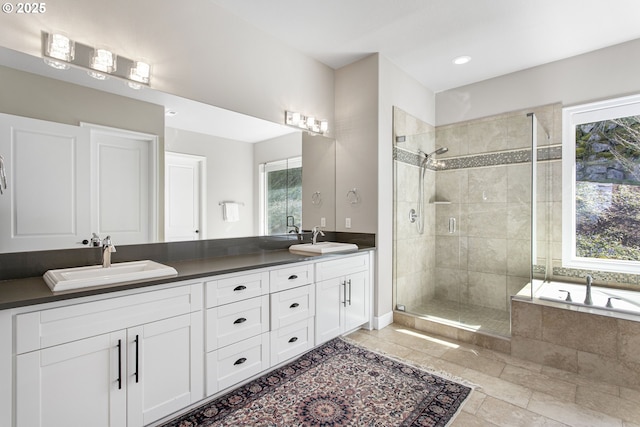 bathroom featuring tile patterned floors, a sink, double vanity, and a stall shower