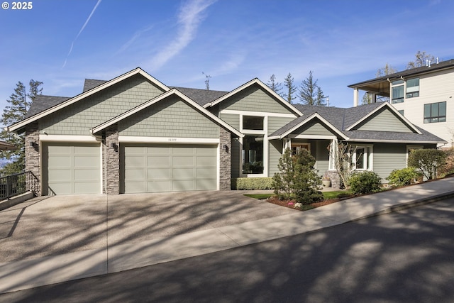 view of front of home featuring stone siding, concrete driveway, roof with shingles, and a garage