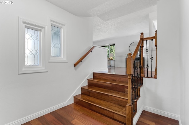 staircase featuring hardwood / wood-style flooring and a textured ceiling