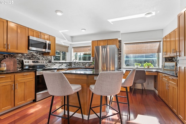 kitchen featuring a breakfast bar, appliances with stainless steel finishes, dark hardwood / wood-style floors, a kitchen island, and decorative backsplash