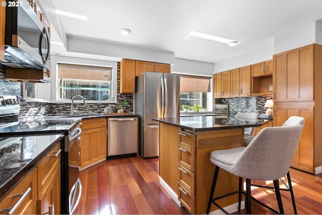 kitchen featuring stainless steel appliances, a center island, a kitchen bar, and dark hardwood / wood-style floors