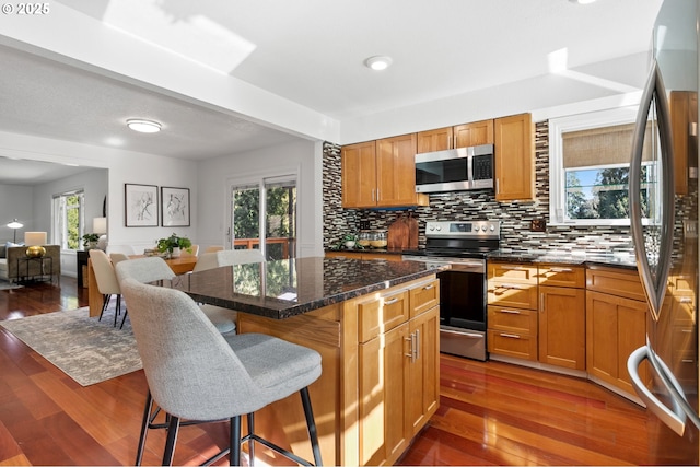 kitchen with a kitchen island, appliances with stainless steel finishes, backsplash, and a kitchen breakfast bar