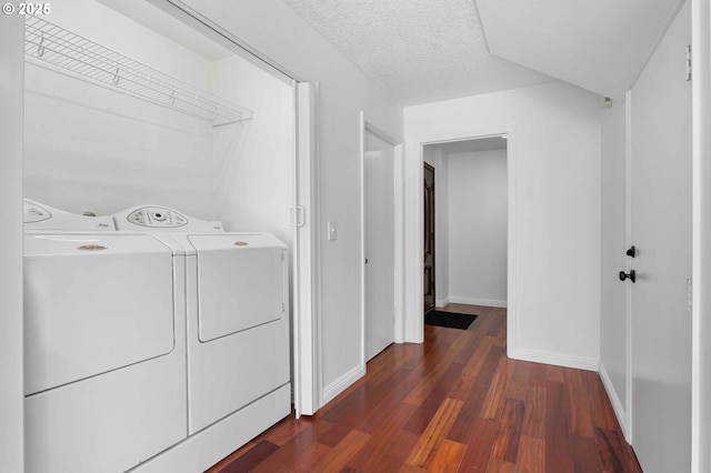 washroom with dark wood-type flooring, washing machine and clothes dryer, and a textured ceiling